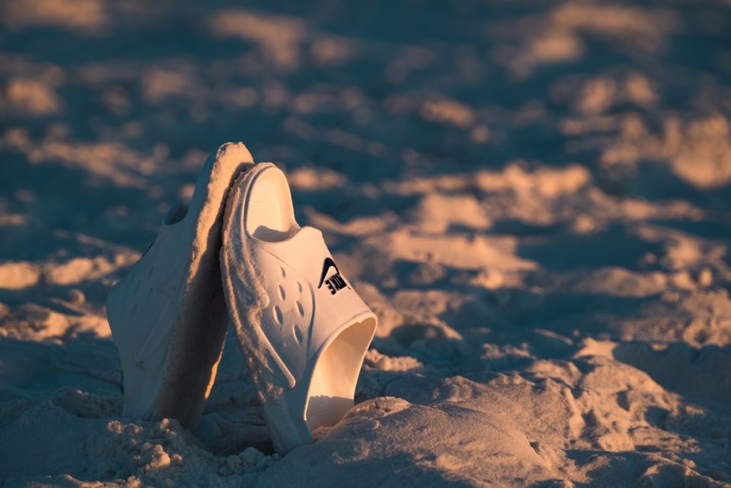 Chinelo Nike enterrado na areia
